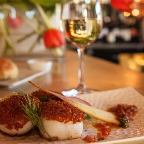 a close up of a plate of food and a glass of wine