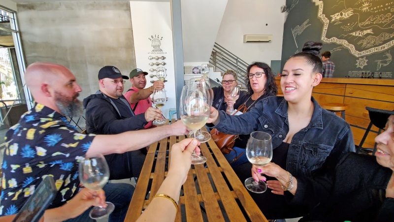 Valley Project cheers a group of people sitting at a table with wine glasses